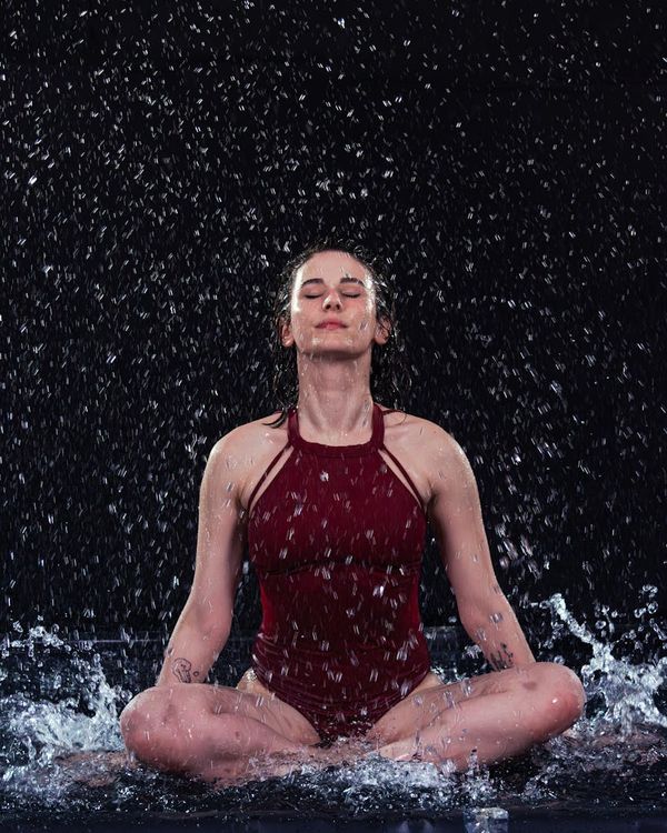Woman in a calm, flowing exercise pose against a dark background with aurora-like highlights.